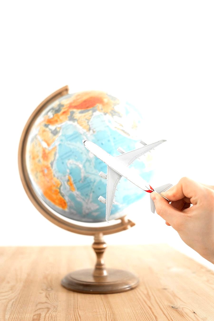 A hand tracing a route on a globe, representing personalised travel planning
